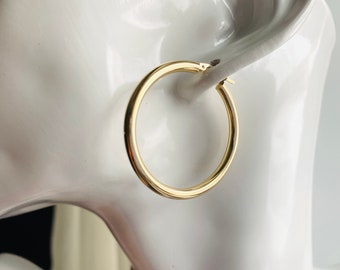 May include: Gold hoop earrings. The earrings are simple and classic, with a smooth, polished finish.