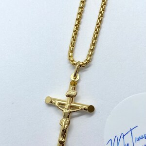 May include: A gold chain necklace with a gold Jesus on the cross pendant.