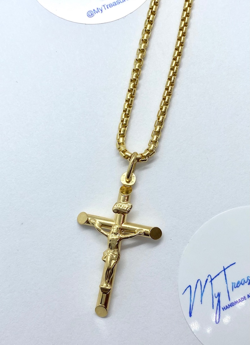May include: A gold chain necklace with a gold Jesus on the cross pendant.