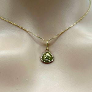 May include: A gold chain necklace with a small, round pendant featuring an angel design.
