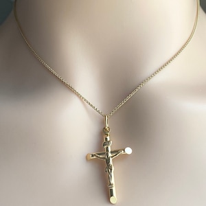 May include: A gold chain necklace with a gold crucifix pendant. The crucifix features a detailed figure of Jesus Christ.
