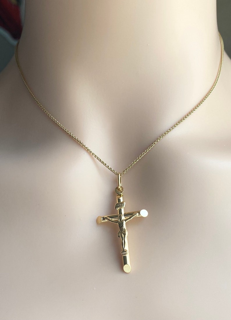 May include: A gold chain necklace with a gold crucifix pendant. The crucifix features a detailed figure of Jesus Christ.