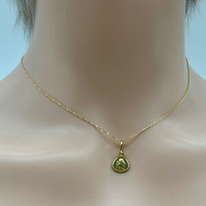 May include: A gold chain necklace with a small gold pendant featuring a detailed image of an angel.