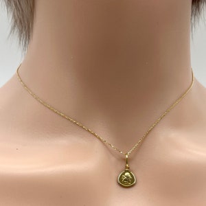 May include: A gold chain necklace with a small pendant featuring an angel design.