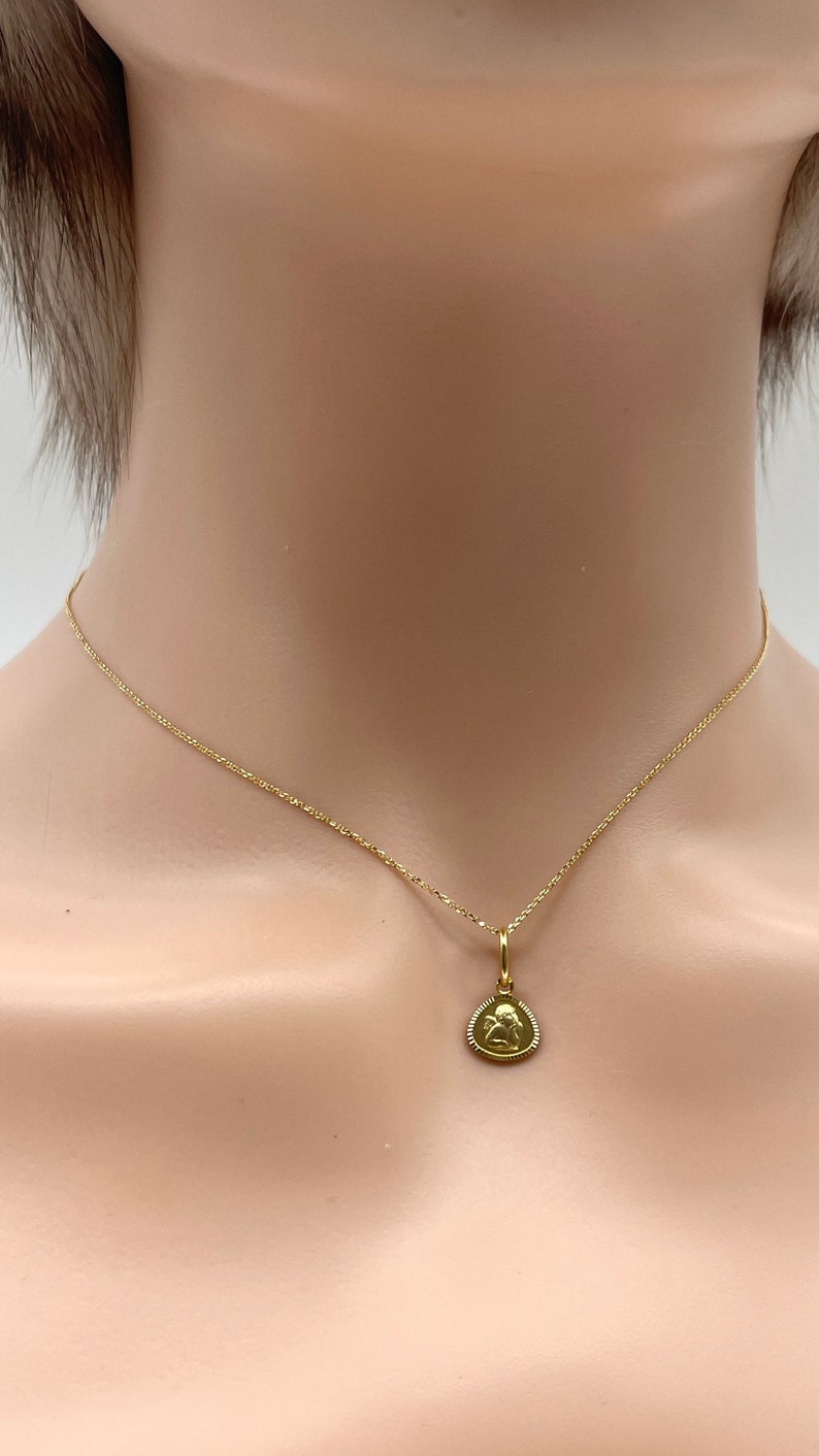 May include: A gold chain necklace with a small pendant featuring an angel design.