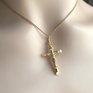 May include: A gold chain necklace with a gold crucifix pendant. The crucifix features a detailed figure of Jesus Christ.