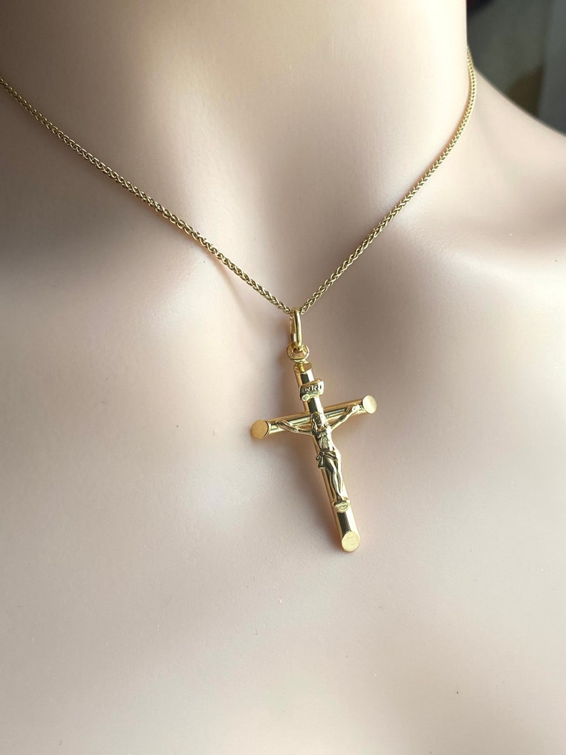May include: A gold chain necklace with a gold crucifix pendant. The crucifix features a detailed figure of Jesus Christ.
