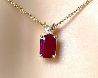 May include: A gold chain necklace with a pendant featuring a red rectangular ruby gemstone and a small diamond accent.