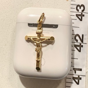 May include: A gold-colored crucifix pendant with a detailed figure of Jesus Christ. The pendant is on a white background with the text "Designed in California, Made in China".