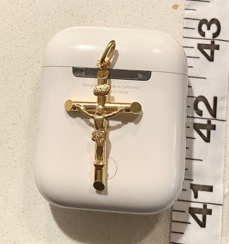 May include: A gold-colored crucifix pendant with a detailed figure of Jesus Christ. The pendant is on a white background with the text "Designed in California, Made in China".