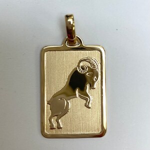Pode incluir: Encanto de pingente de ouro com uma representa&ccedil;&atilde;o detalhada do signo do zod&iacute;aco &Aacute;ries, um carneiro com chifres encaracolados, sobre um fundo texturizado.