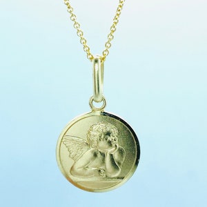 May include: A gold chain necklace with a round pendant featuring a detailed image of a cherub angel with wings.
