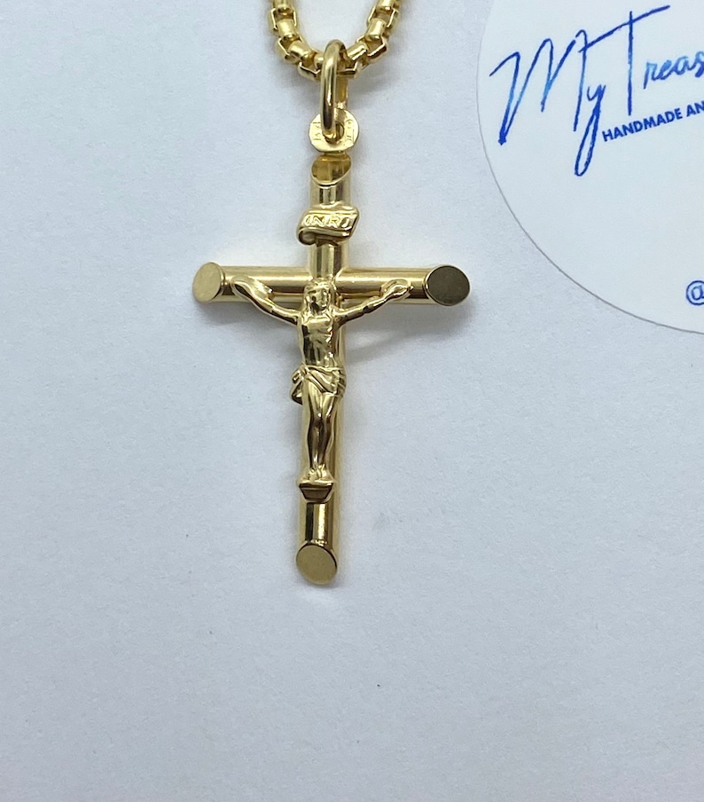 May include: A gold-tone pendant necklace featuring a crucifix with a small figure of Jesus Christ. The pendant is attached to a delicate chain.