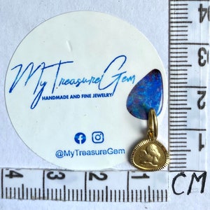 May include: Gold-toned pendant charm featuring a detailed angel design. The charm is approximately 1 cm in size and is shown next to a ruler for scale.