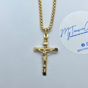 May include: A gold chain necklace with a gold crucifix pendant. The crucifix features a detailed figure of Jesus Christ.