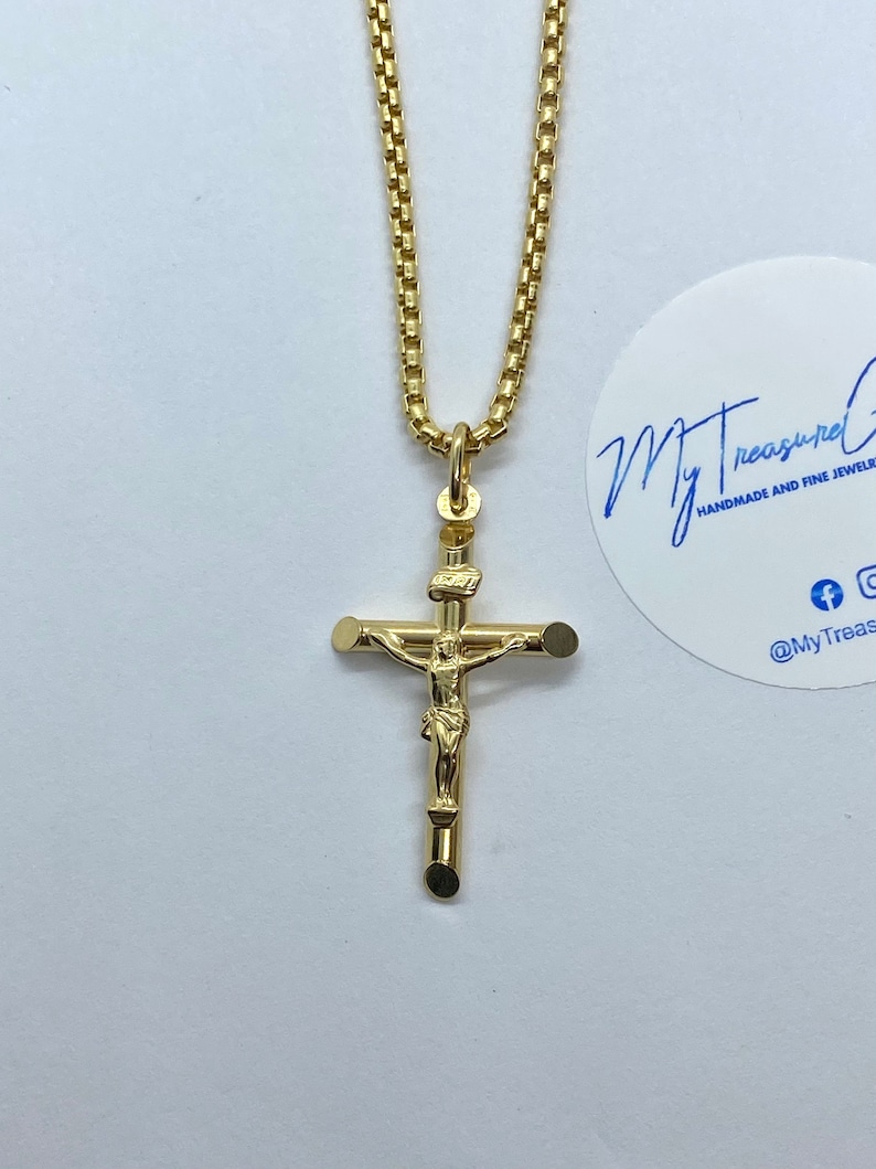 May include: A gold chain necklace with a gold crucifix pendant. The crucifix features a detailed figure of Jesus Christ.