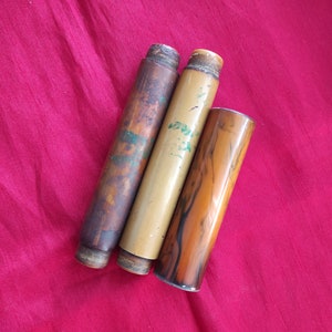 Może przedstawiać: Trzy vintage drewniane etui na długopisy, jedno jest brązowe z zielonymi akcentami, jedno jest beżowe z zielonymi akcentami, a jedno jest brązowe z czarnymi paskami.