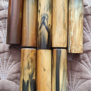May include: Eight wooden dowels with a natural brown and black marbled pattern. The dowels are arranged in two rows, with four in each row.
