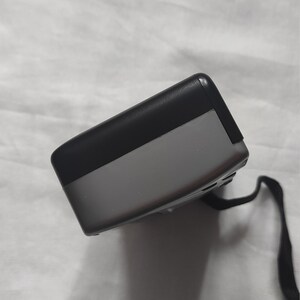 Puede incluir: Un dispositivo electr&oacute;nico negro y gris con una correa negra. El dispositivo tiene una forma rectangular y una superficie lisa.