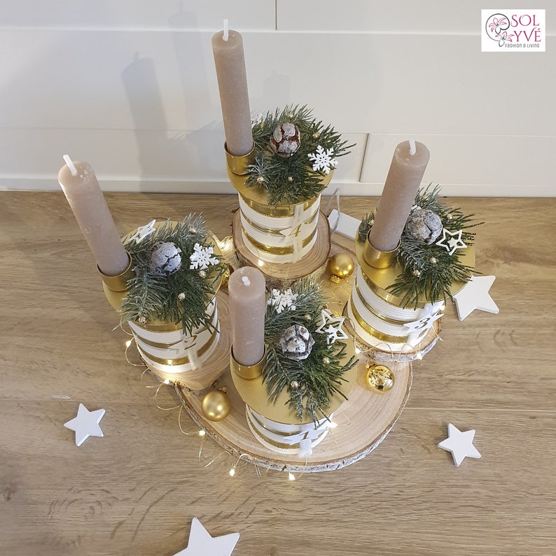 May include: A gold and white candle holder with four candles, decorated with pine branches, white snowflakes, and gold ornaments. The candle holder is on a wooden base.