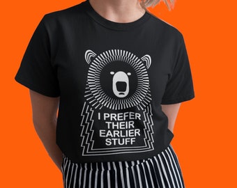 Può includere: Maglietta nera con una grafica bianca di un muso d'orso all'interno di un cerchio con il testo "I prefer their earlier stuff" sotto.