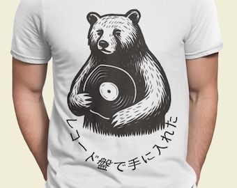Può includere: T-shirt bianca con un'illustrazione in bianco e nero di un orso che tiene in mano un disco in vinile. Il testo giapponese circonda l'orso. La pelliccia dell'orso è dettagliata e il disegno è centrato sulla maglietta.