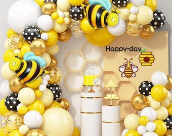 May include: A bee-themed party decoration set with yellow, white, black, and gold balloons. The balloons are arranged in an arch shape and include bee-shaped balloons, honeycomb balloons, and polka dot balloons. The text "Happy-day" is written on a yellow background.