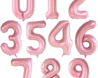 May include: Ten pink foil balloons shaped like the numbers 0 through 9. The balloons are inflated and ready to be used for a party or celebration.