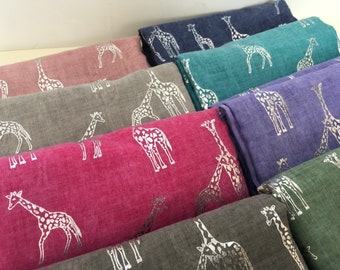 May include: A stack of ten scarves with a silver giraffe print on a variety of colored fabrics, including pink, gray, teal, blue, and purple.