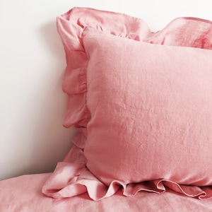 May include: A pink ruffled pillowcase made from soft, textured linen.