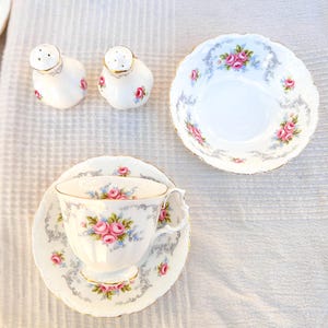 Puede incluir: Juego de té de porcelana blanca con un diseño de rosas. El juego incluye una taza y platillo, un cuenco pequeño y dos saleros. Los bordes están adornados con oro.