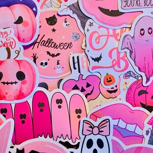 May include: A collection of pink and purple Halloween stickers featuring ghosts, pumpkins, and the words "Happy Halloween".