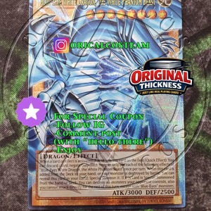 May include: A Blue-Eyes White Dragon, The White Phantom Beast trading card featuring a blue dragon illustration, eight orange level stars, and text including ATK/3000 DEF/2500. The card displays promotional text for Oricalcosteam and Original Thickness.