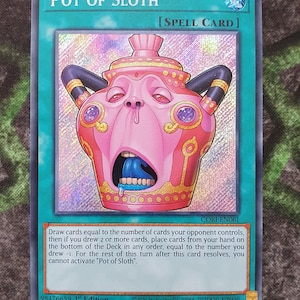 May include: A Pot of Sloth trading card featuring a pink, anthropomorphic pot with a wide-open mouth, blue tongue, and black handles. The card includes the text Pot of Sloth, Spell Card, and game instructions, with a holographic finish on the central art.