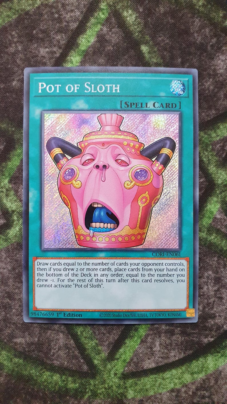 May include: A Pot of Sloth trading card featuring a pink, anthropomorphic pot with a wide-open mouth, blue tongue, and black handles. The card includes the text Pot of Sloth, Spell Card, and game instructions, with a holographic finish on the central art.