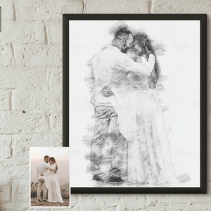 May include: A black and white pencil sketch of a couple embracing. The man is wearing a white shirt and the woman is wearing a white dress. The sketch is framed in a black frame.