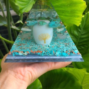 May include: A clear glass pyramid with a gold wire spiral and a white ceramic orb with a gold tree design. The pyramid is filled with turquoise and white stones.
