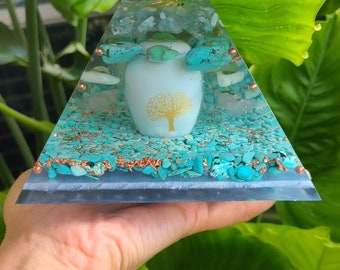 May include: A clear glass pyramid with a gold wire spiral and a white ceramic orb with a gold tree design. The pyramid is filled with turquoise and white stones.