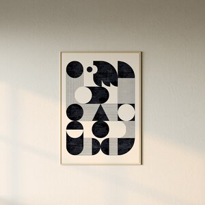 Puede incluir: Un sof&aacute; modular beige con una gran impresi&oacute;n geom&eacute;trica en blanco y negro enmarcada colgada en la pared detr&aacute;s de &eacute;l. El sof&aacute; est&aacute; en una sala de estar moderna con una mesa de caf&eacute; blanca y una cesta tejida.