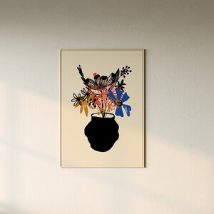Pu&ograve; includere: Un divano componibile beige con una grande stampa incorniciata di un vaso nero con fiori colorati su sfondo bianco. Il divano si trova in un soggiorno con un tavolino da caff&egrave; bianco e un cesto intrecciato.