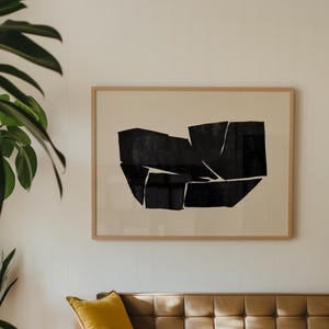 K&ouml;nnte beinhalten: Ein braunes Ledersofa mit einem gelben Kissen vor einem schwarz-wei&szlig;en abstrakten Kunstdruck in einem Holzrahmen.