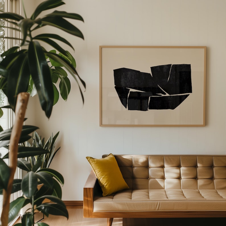 K&ouml;nnte beinhalten: Ein braunes Ledersofa mit einem gelben Kissen vor einem schwarz-wei&szlig;en abstrakten Kunstdruck in einem Holzrahmen.