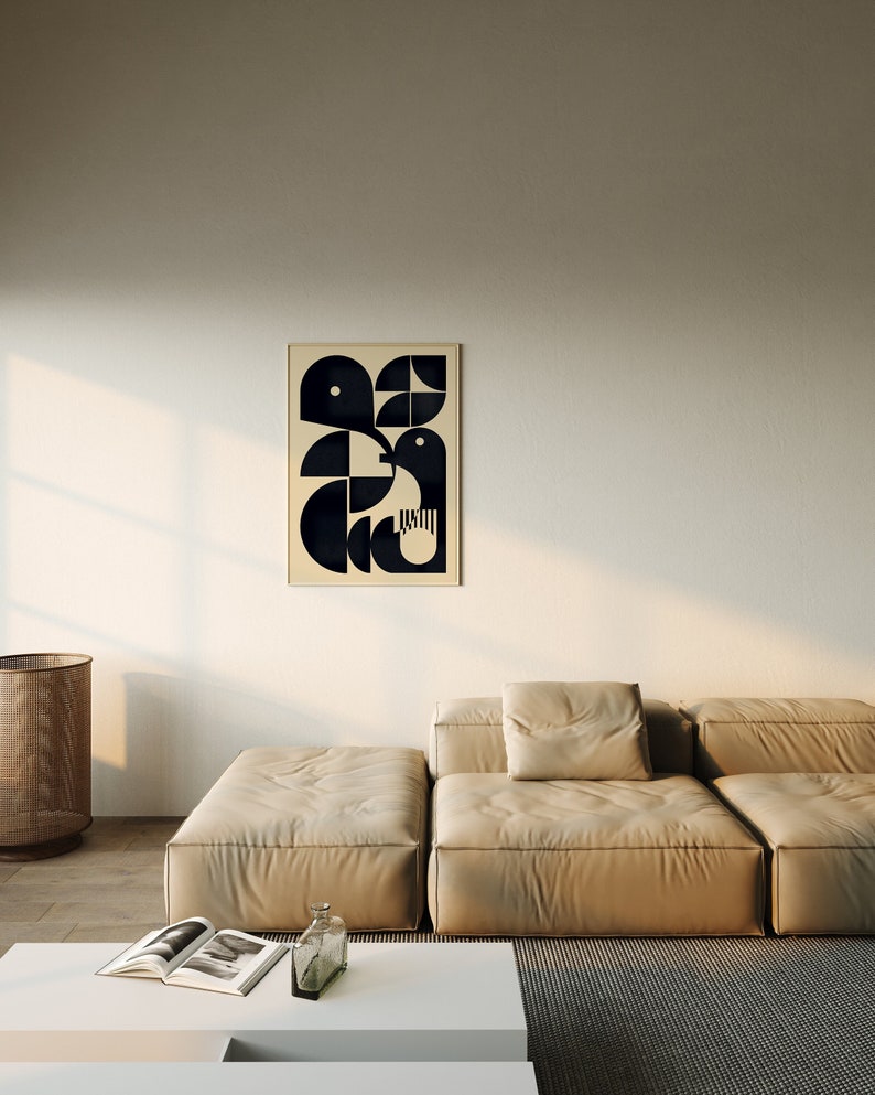 May include: A beige sectional sofa with a black and white geometric print on the wall behind it. The sofa is in a living room with a white coffee table and a wicker basket.