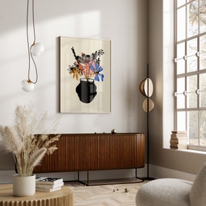 Pu&ograve; includere: Una stampa incorniciata di un arrangiamento floreale stilizzato in un vaso nero. I fiori sono in tonalit&agrave; di blu, rosa, arancio e giallo. Lo sfondo &egrave; beige chiaro.