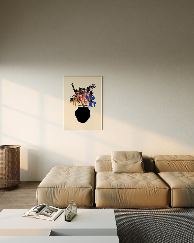 Pu&ograve; includere: Un divano componibile beige con una grande stampa incorniciata di un vaso nero con fiori colorati su sfondo bianco. Il divano si trova in un soggiorno con un tavolino da caff&egrave; bianco e un cesto intrecciato.
