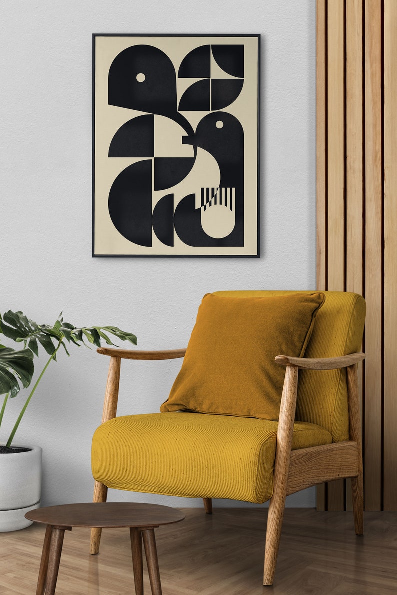 May include: A black and white geometric abstract art print in a black frame hanging on a white wall above a mustard yellow armchair with a wooden frame.