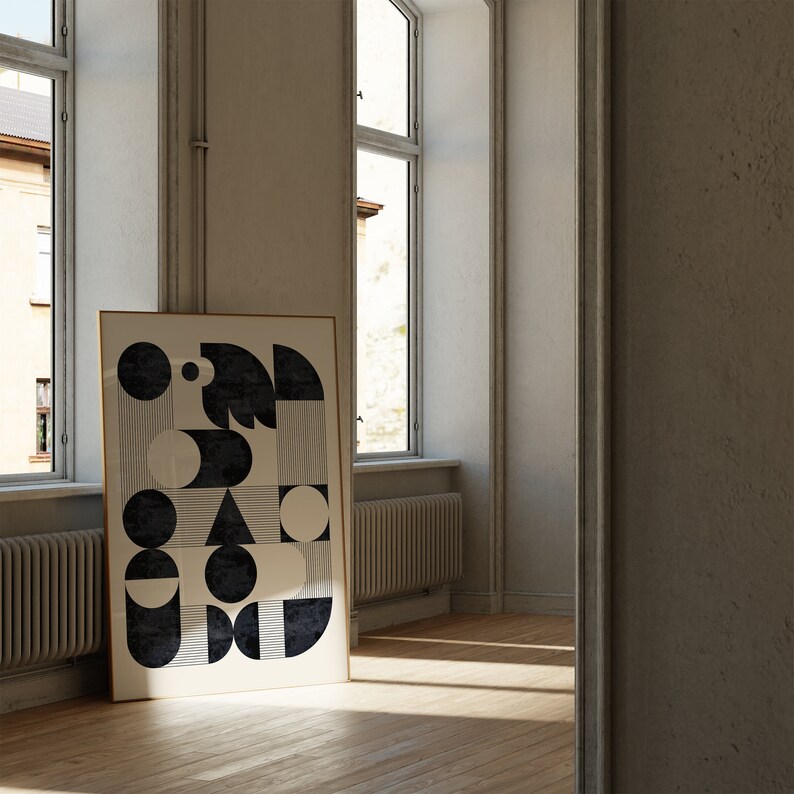 Puede incluir: Una impresi&oacute;n de arte abstracto geom&eacute;trico en blanco y negro en un marco dorado colgado en una pared blanca en una habitaci&oacute;n con dos ventanas.