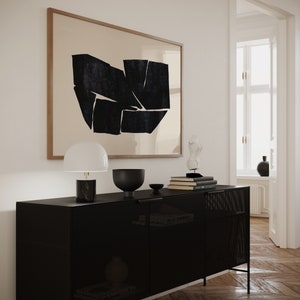 K&ouml;nnte beinhalten: Ein schwarzer Metallschrank mit einer Drahtgitterfront und zwei T&uuml;ren. Der Schrank steht auf einem Holzboden und hat eine Lampe, eine Sch&uuml;ssel und B&uuml;cher darauf. An der Wand hinter dem Schrank h&auml;ngt ein gerahmtes abstraktes Kunstbild.