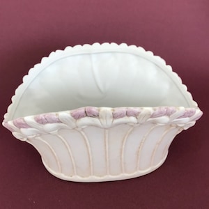 May include: White ceramic planter with a scalloped rim and pink floral details. The planter is shaped like a half-circle and has a fluted design.