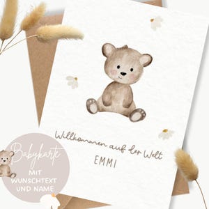 Könnte beinhalten: Eine weiße Grußkarte mit einer Aquarellillustration eines braunen Teddybären, der zwischen kleinen weißen Blumen sitzt. Die Karte enthält den Text Willkommen auf der Welt und den Namen EMMI in einer einfachen dunkelbraunen Schrift.